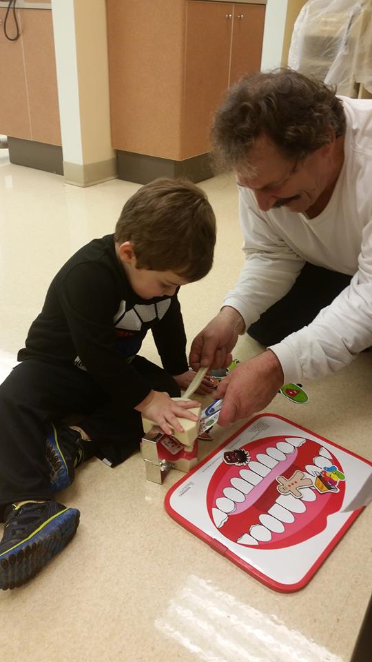 A grandfather unable to walk well, still willing to get on the floor to talk teeth and play with his grandson.