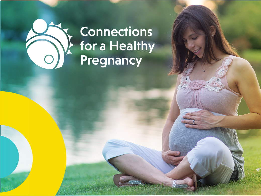 pregnant woman sitting in grass by lake