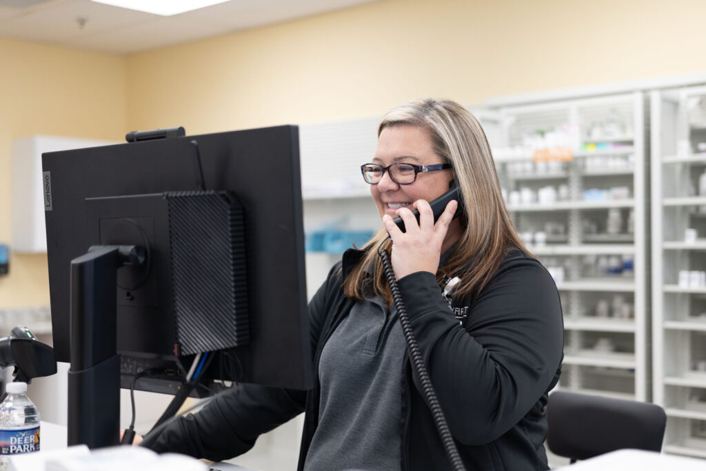 Pharmacy cashier helping a customer over the phone with their new prescription